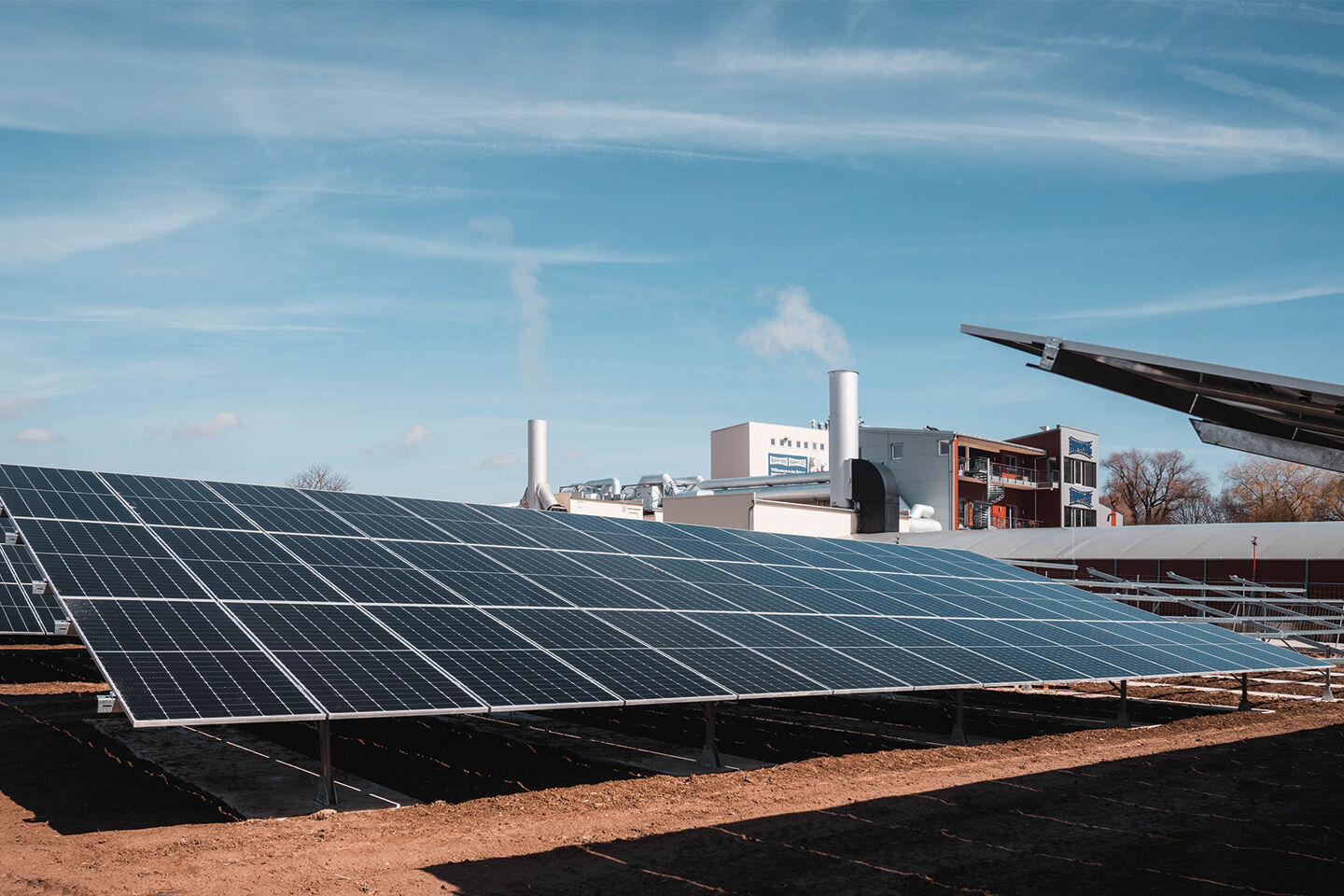 Ein Solarfeld steht vor einem Firmengebäude.