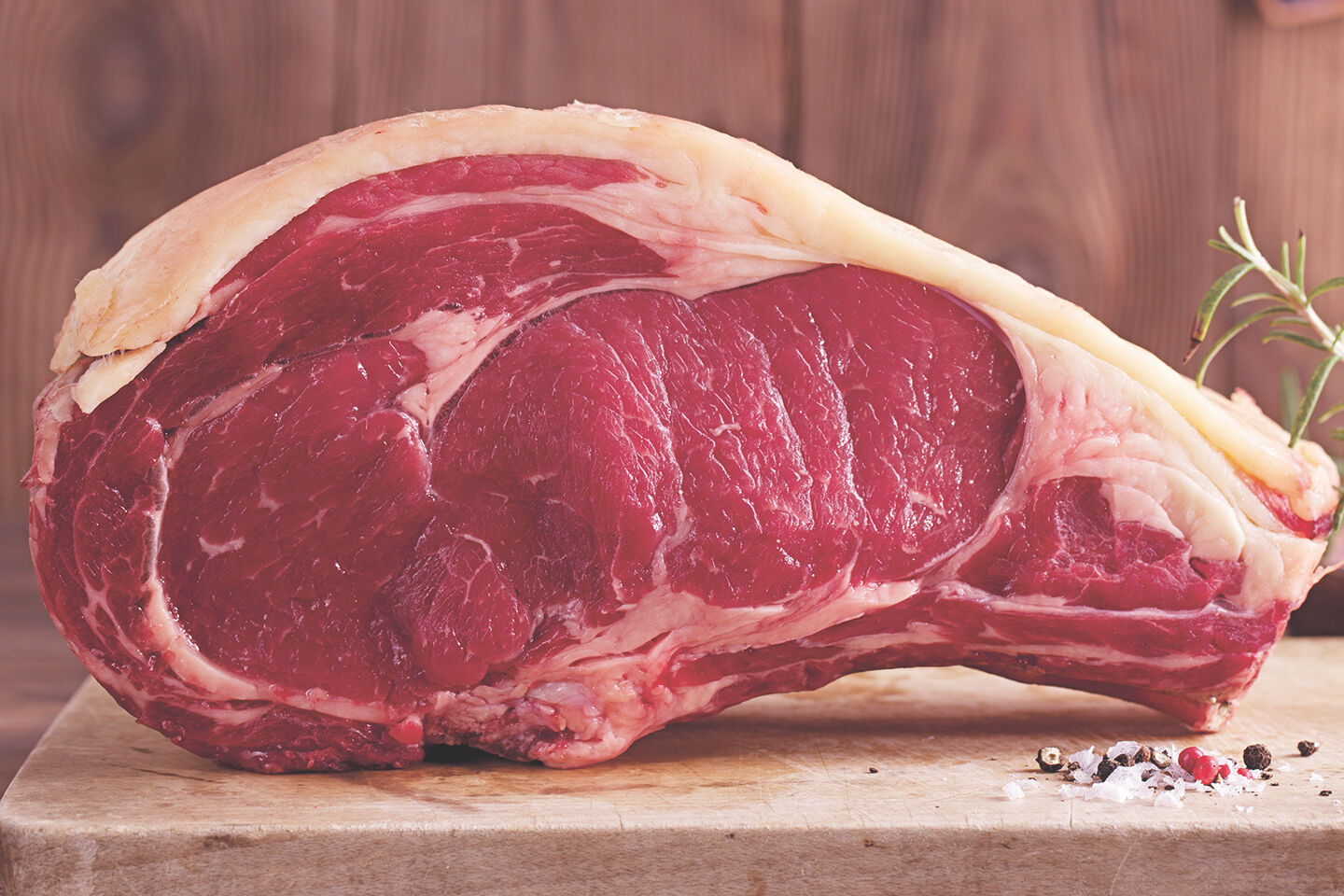 Ein großes Stück rohes Fleisch liegt auf einem Holzbrett.