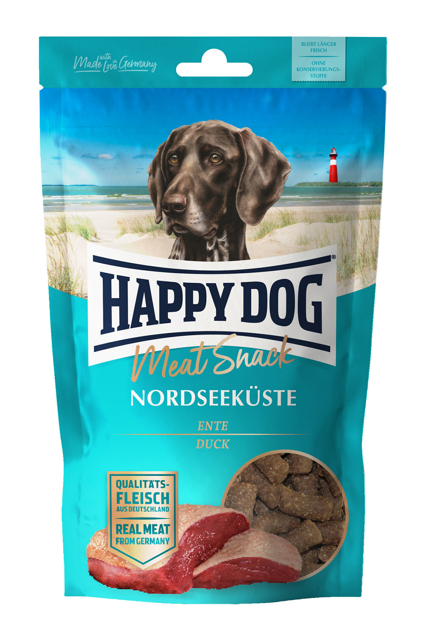 Verpackung mit Bild eines Hundes, Text „HAPPY DOG Meat Snack Nordseeküste Ente“, Landschaftshintergrund mit Leuchtturm, und einem Aufkleber „Qualitätsfleisch aus Deutschland“.