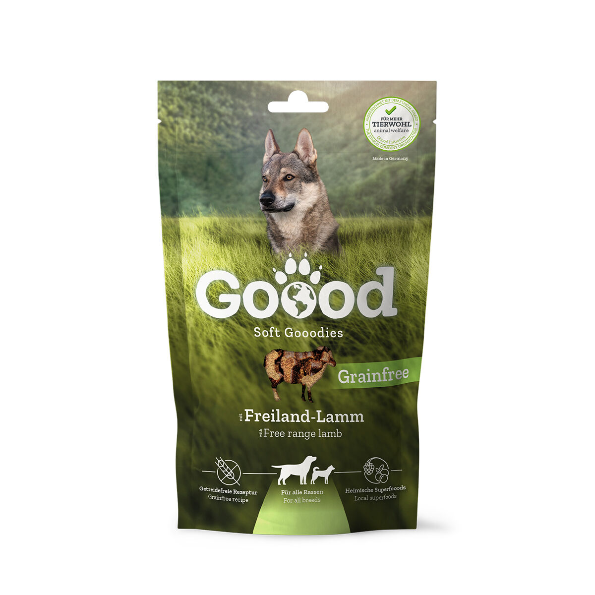 Verpackung für Hundesnacks namens "Goood Soft Goodies" mit Freiland-Lamm, getreidefrei, für alle Rassen. Bild eines Hundes auf einer grünen Wiese; Text auf Englisch und Deutsch.