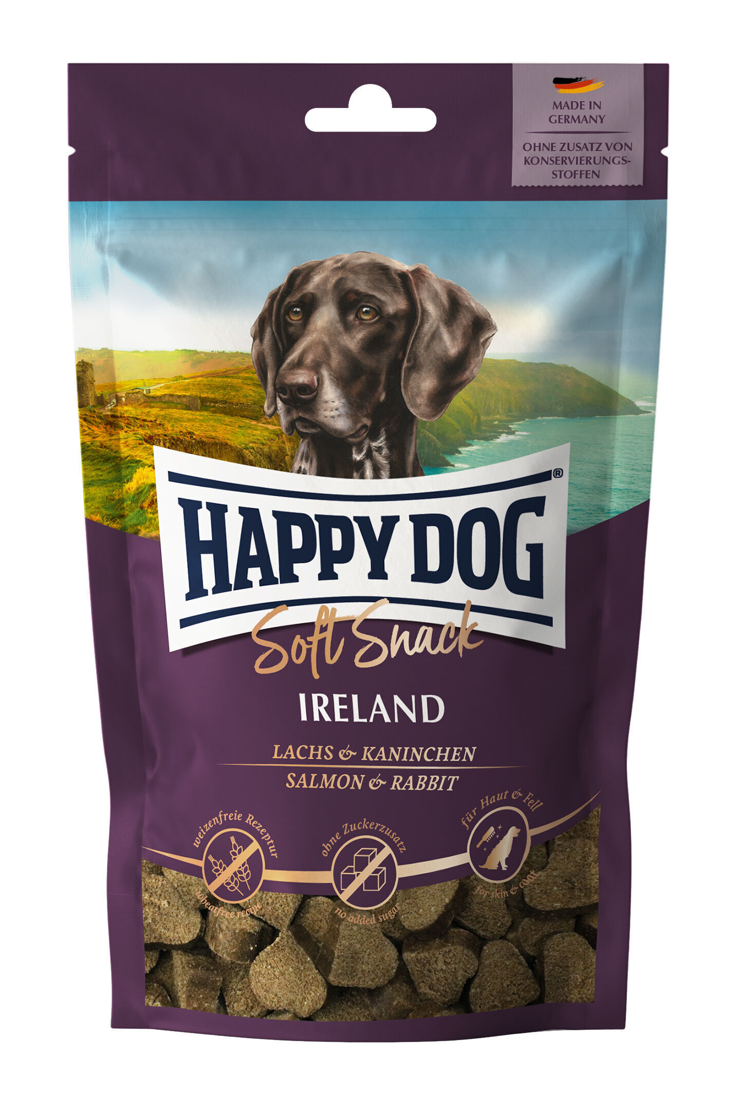 Verpackung mit Hundebild, Landschaft im Hintergrund. Text: "Happy Dog Soft Snack Ireland Lachs & Kaninchen, Made in Germany, ohne Zusatz von Konservierungsstoffen". Enthält kleine braune Snacks.