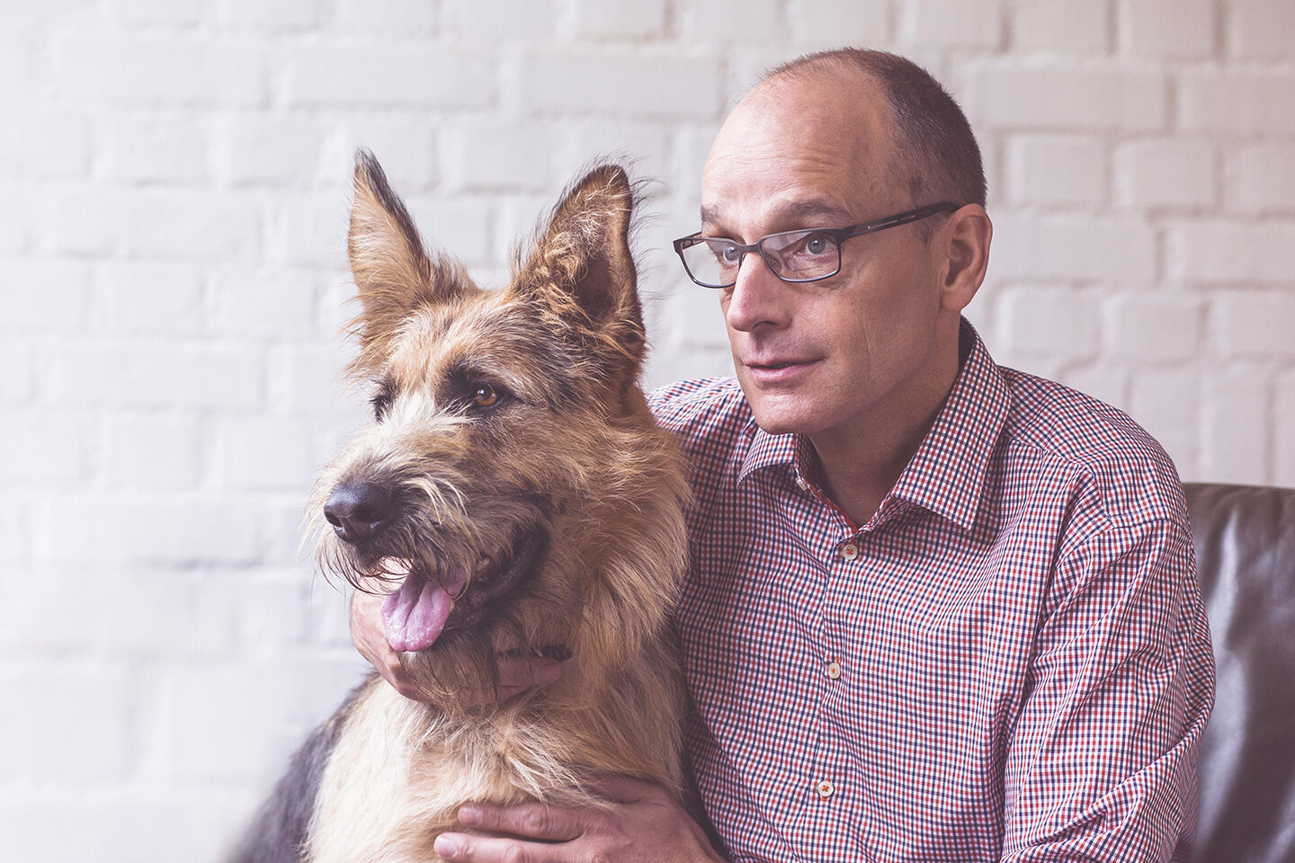 Geschäftsführer Georg Müller und sein Tierschutzhund sitzen gemeinsam auf einem Ledersessel