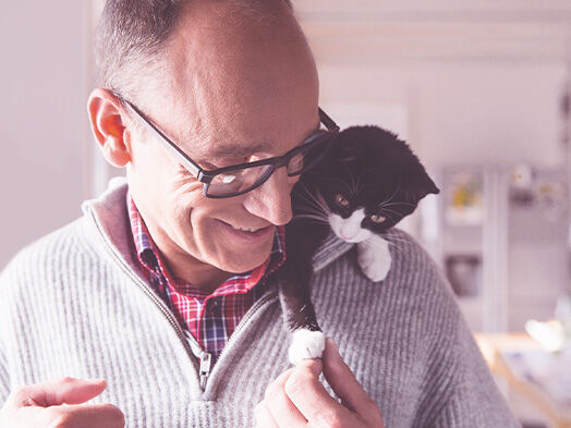 Geschäftsführer Georg Müller mit einem kleinen schwarz-weißem Kätzchen auf der Schulter