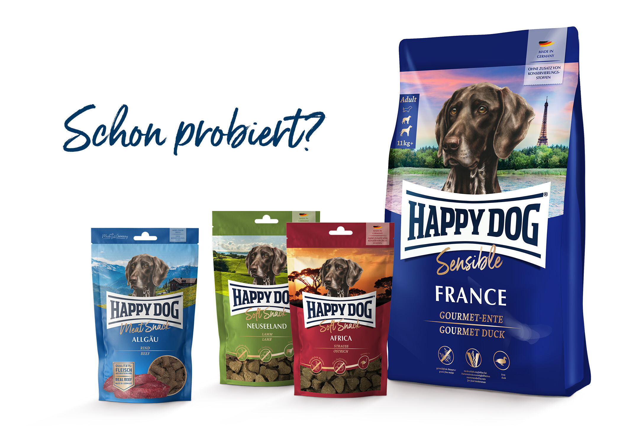 Vier bunte Verpackungen von Happydog Hundefutter stehen nebeneinander; Text „Schon probiert?“ suggeriert Probieraufforderung. Verpackungsfarben: Blau, Grün, Rot, Blau mit großem Hundemotiv.