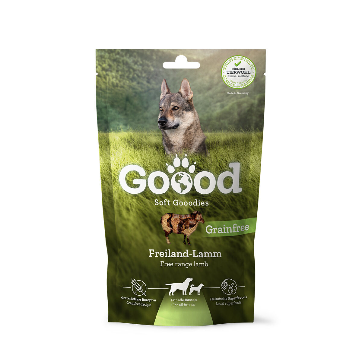 Verpackung für Hundesnacks namens "Goood Soft Goodies" mit Freiland-Lamm, getreidefrei, für alle Rassen. Bild eines Hundes auf einer grünen Wiese; Text auf Englisch und Deutsch.