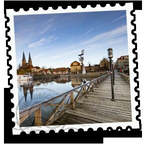 Briefmarke einer Stadt am Fluss mit Brücke.