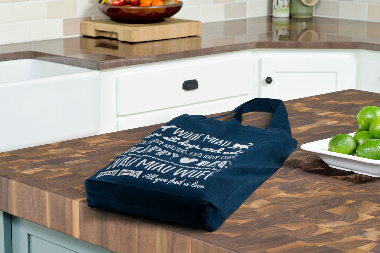 Eine Baumwolltasche mit Schriftzügen von Hunden-und Katzenlauten liegt auf einem Küchentresen.