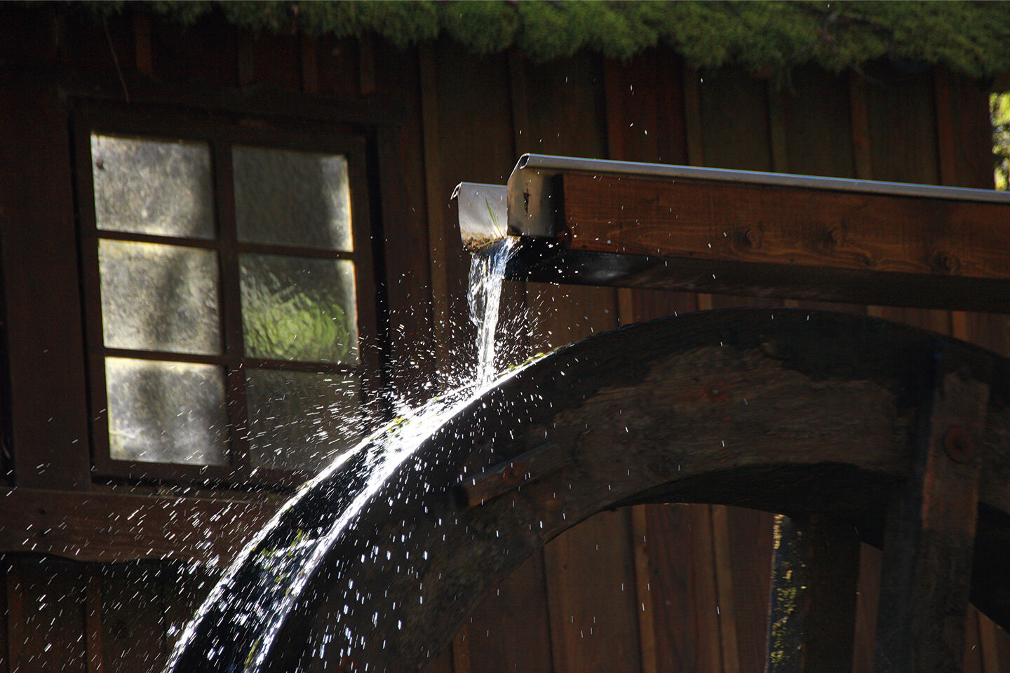 Darstellung eines Wasserrads in einem Schuppen.