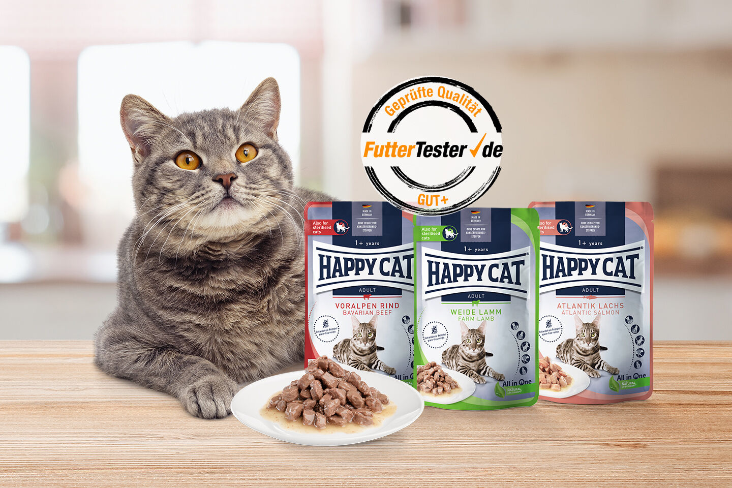 Katze sitzt neben drei "Happy Cat" Futtersorten, Voralpen Rind, Weide Lamm, Atlantik Lachs. Teller mit Futter vorne. Prüfsiegel "FutterTester.de" oben.