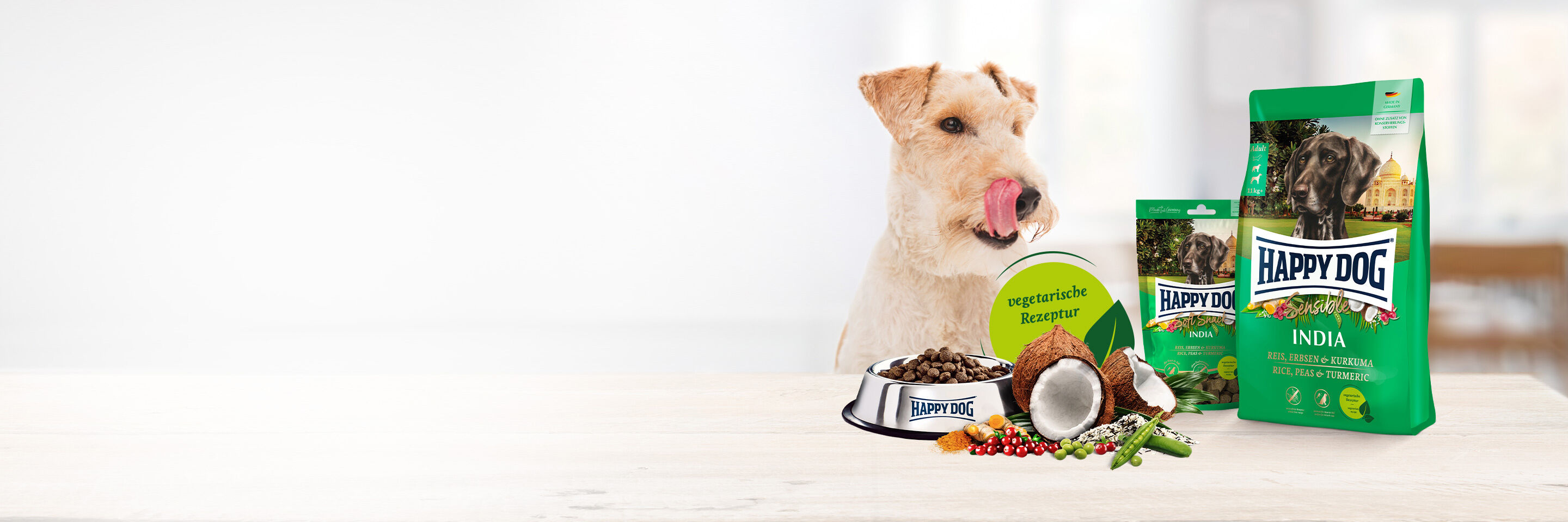 Ein weißer Hund schleckt sich das Maul. Vor ihm steht vegetarisches Hundefutter.