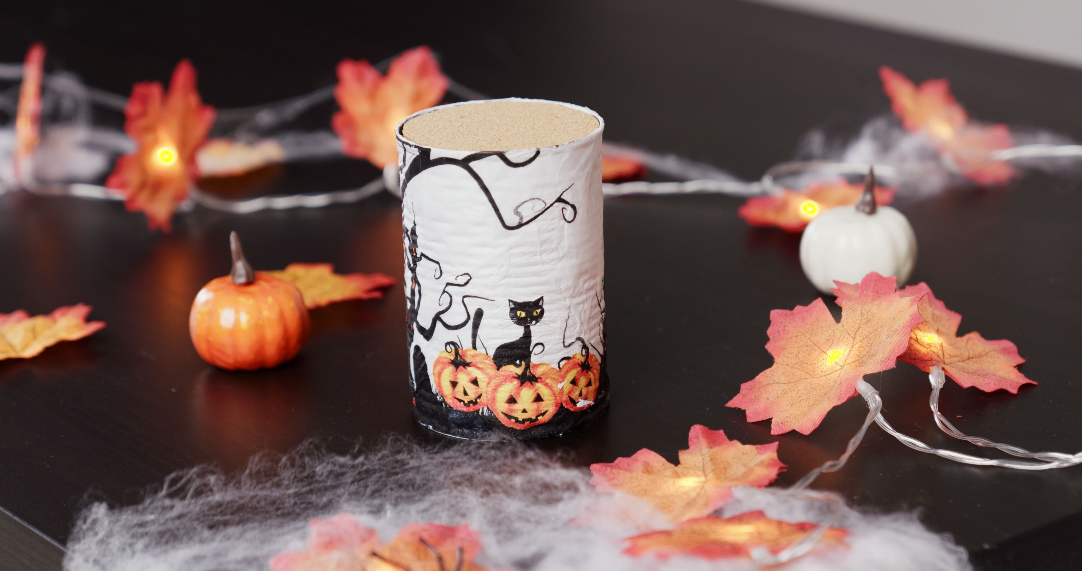 Eine für Halloween dekorierte Hundefutterdose steht auf einem Tisch, welcher mit Watte und Kürbissen für Halloween dekoriert ist.