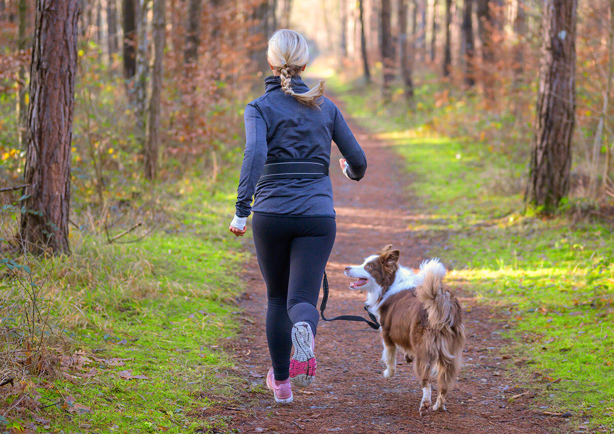 Eine Frau joggt mit ihrem Hund an einer Joggingleine