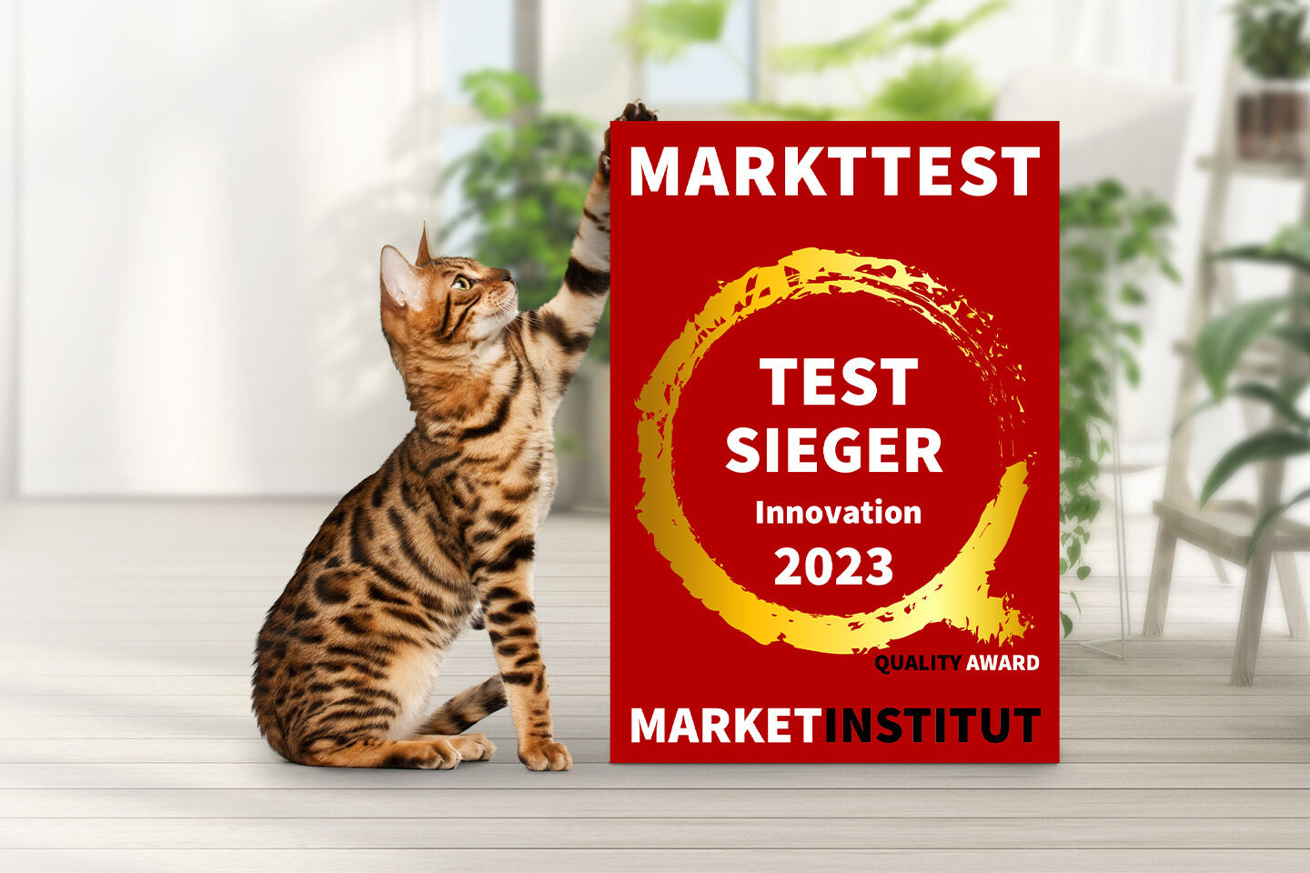 Katze berührt mit Pfote rotes Schild. Text: "Markttest Testsieger Innovation 2023 Quality Award Marketinstitut." Hintergrund: Zimmerpflanzen in hellem Raum.