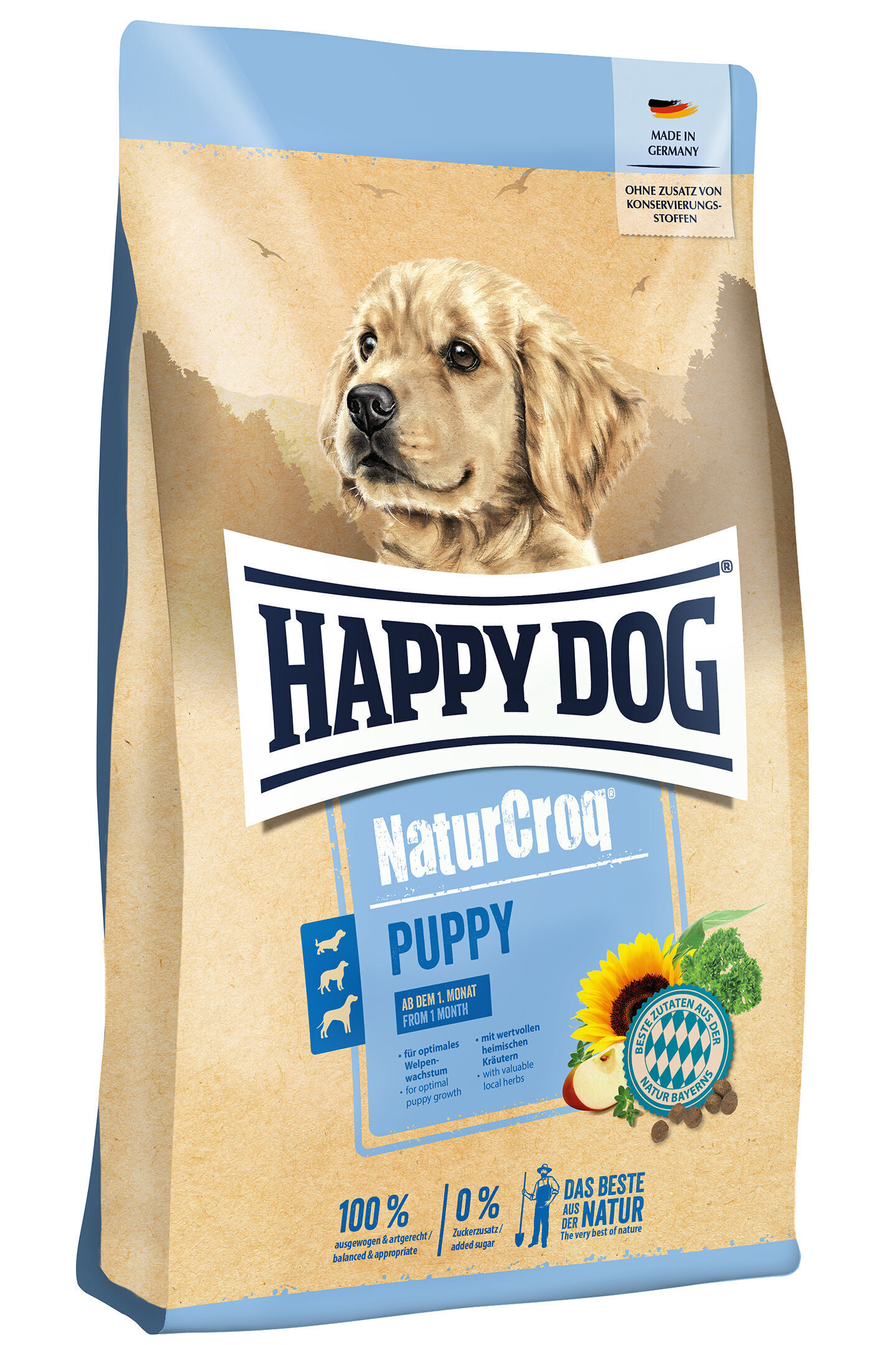 NaturCroq Puppy Hundewelpe auf Futtersackabbildung, sitzt vor blau-beigem Hintergrund. Text: "Happydog NaturCroq Puppy", "Made in Germany", "Ohne Zusatz von Konservierungsstoffen", "Ab dem 1. Monat".