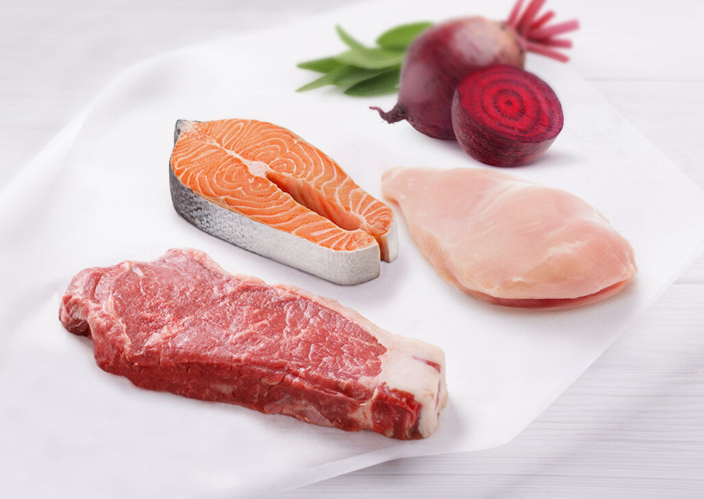 Rohes Rindfleisch, Lachs, Hühnerbrust und Rote Beete als Zutaten für Katzenfutter liegen auf dem Tisch