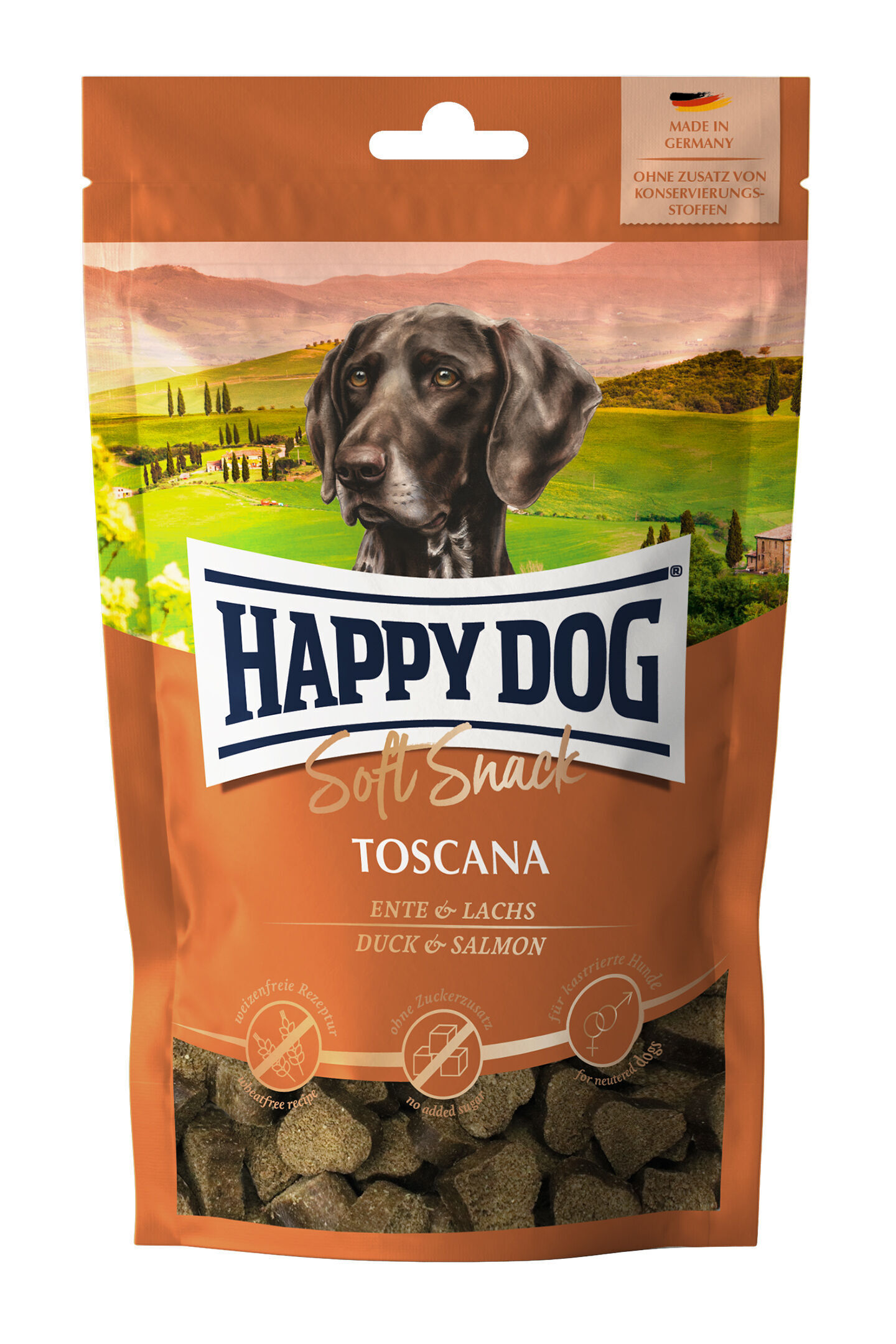 Packung Hundesnacks mit der Aufschrift "Happy Dog Soft Snack Toscana, Ente & Lachs." Illustration eines Hundes und toskanischer Landschaft im Hintergrund. "Made in Germany, ohne Zusatz von Konservierungsstoffen."