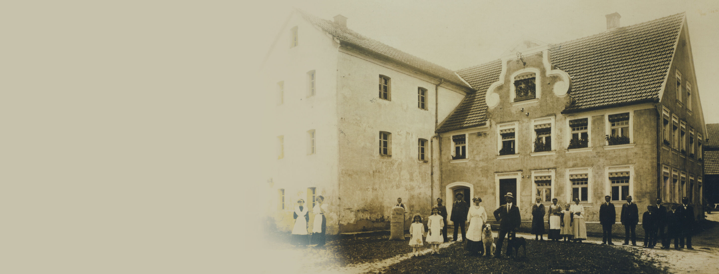 Vor einem früheren Bauernhaus steht eine Familie mit Hunden.